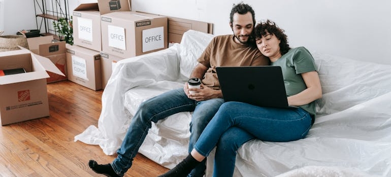 A couple sitting on a sofa browsing the internet about on why millennials move to small towns