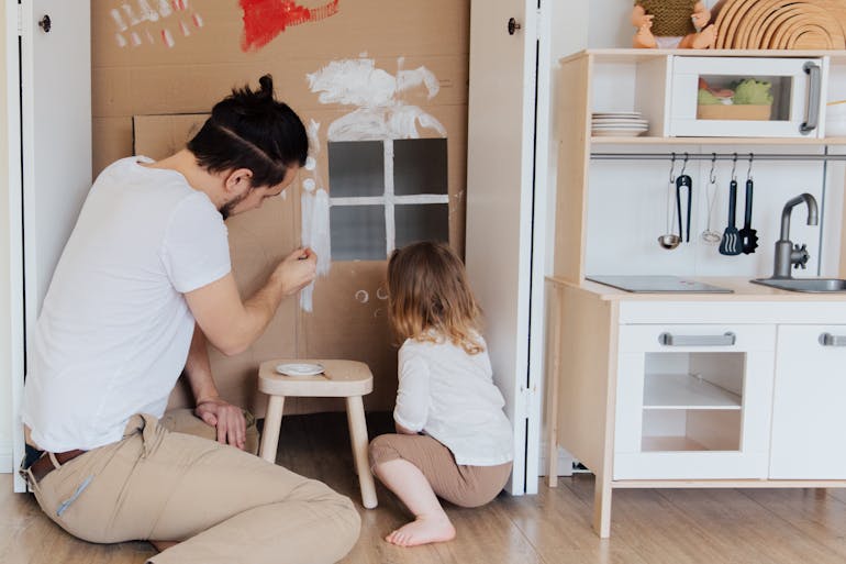 A Man Painting a Cardboard with his daughter