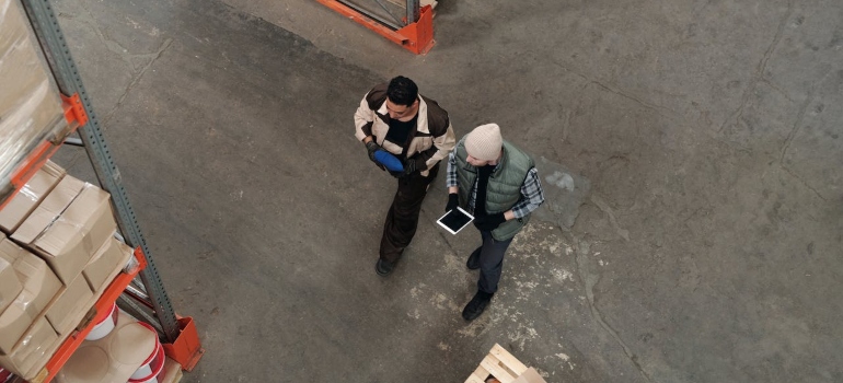 Men Working in a Warehouse wear a tablet discuss pros and cons of LTL shipping