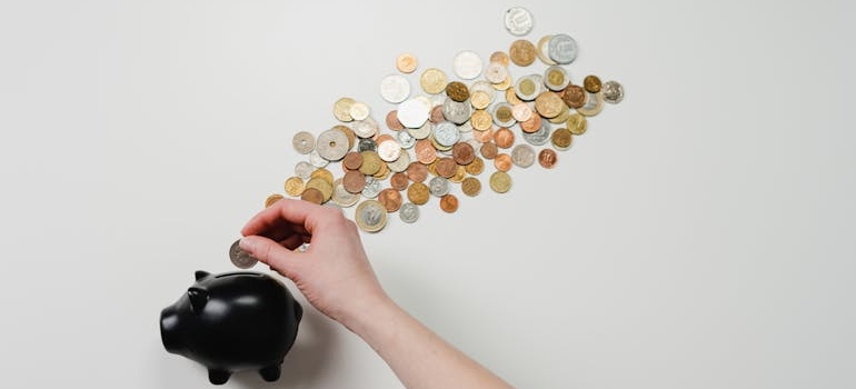 A person Putting Coin in a black Piggy Bank