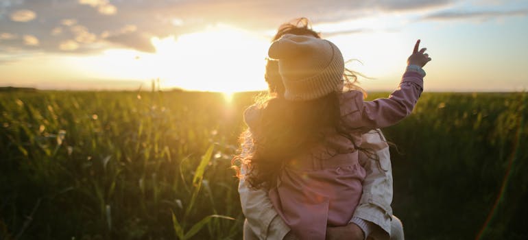a woman holding her baby during the sunset