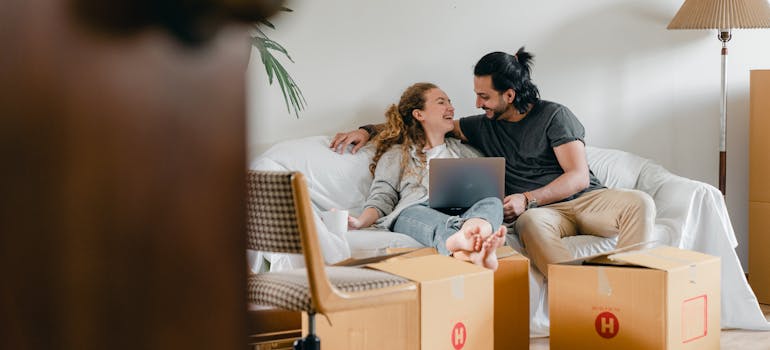 a happy couple sitting among moving boxes