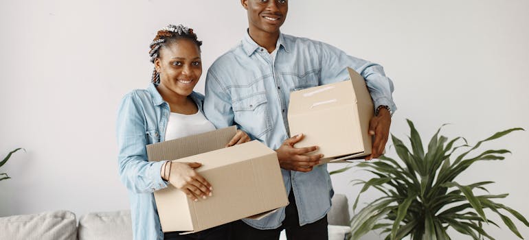 a happy couple holding moving boxes after moving from Kuna ID to Seattle